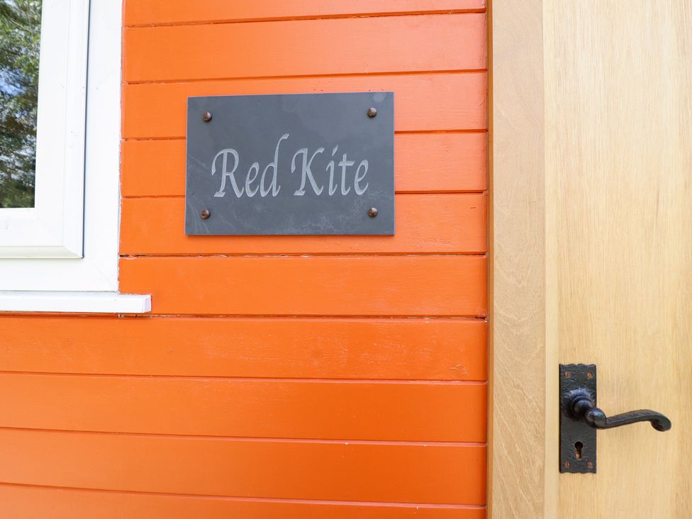 A sign labeled Red Kite on an orange wall at Red Kite at Wild Valley Huts in Llanrhaeadr-Ym-Mochnant