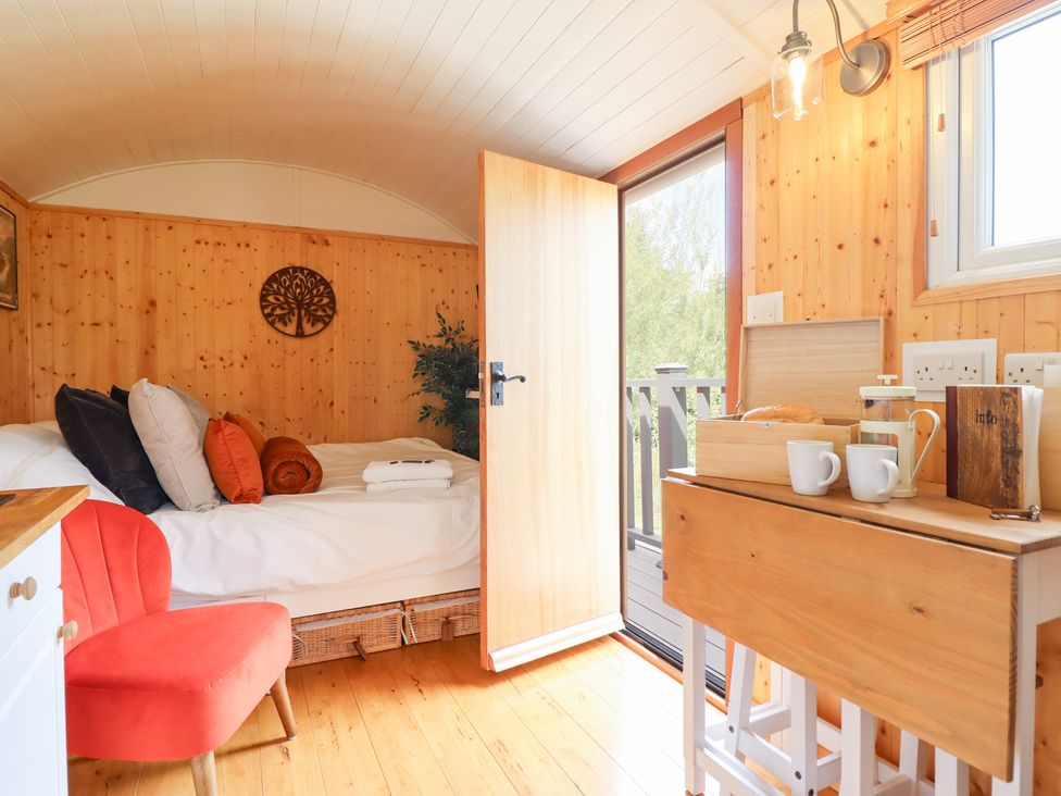 A bedroom with a bed and a table with mugs and bread at Red Kite at Wild Valley Huts Llanrhaeadr-Ym-Mochnant