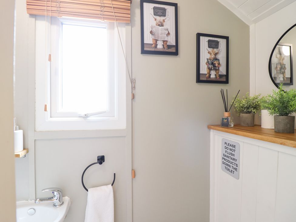 A bathroom with a sink and wall art at Red Kite at Wild Valley Huts Llanrhaeadr-Ym-Mochnant