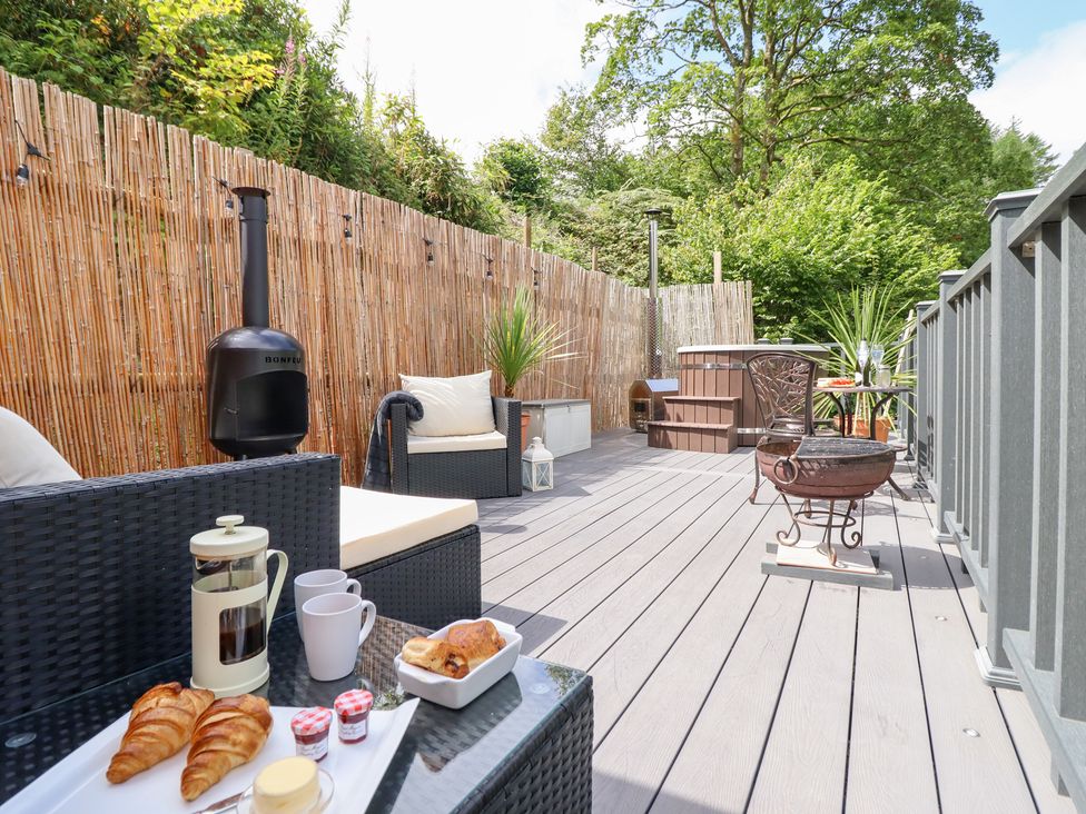 An outdoor deck with seating and a hot tub at Red Kite at Wild Valley Huts Llanrhaeadr-Ym-Mochnant