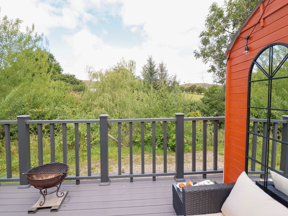 An outdoor area with a deck, barbecue, and seating at Red Kite at Wild Valley Huts, Llanrhaeadr-Ym-Mochnant