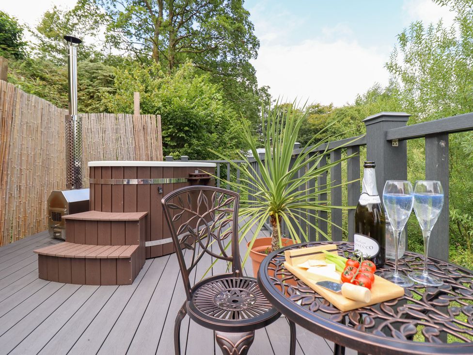 An outdoor seating area with a hot tub and table at Red Kite at Wild Valley Huts Llanrhaeadr-Ym-Mochnant