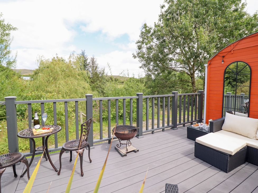An outdoor deck with a table, chairs, and a grill at Red Kite at Wild Valley Huts in Llanrhaeadr-Ym-Mochnant