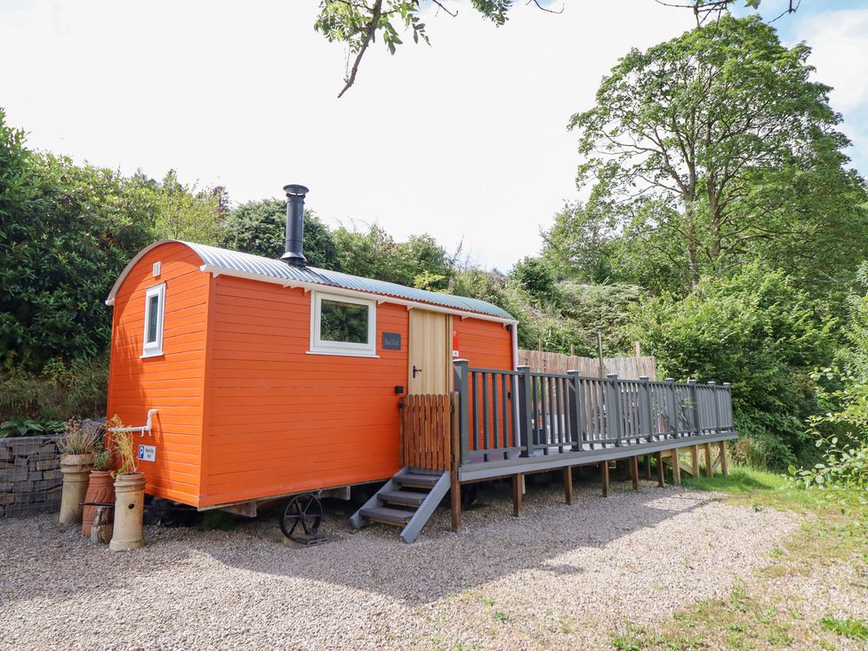 A shepherd's hut with a wooden deck at Red Kite at Wild Valley Huts Llanrhaeadr-Ym-Mochnant