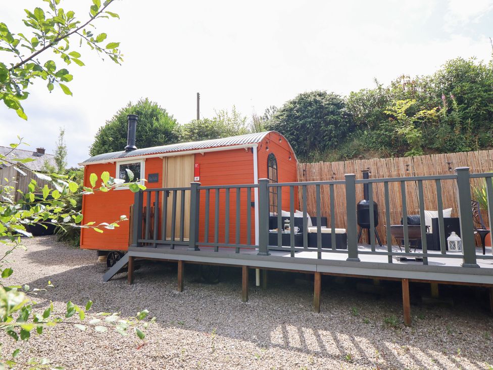 A shepherd's hut with a deck and outdoor seating at Red Kite at Wild Valley Huts Llanrhaeadr-Ym-Mochnant