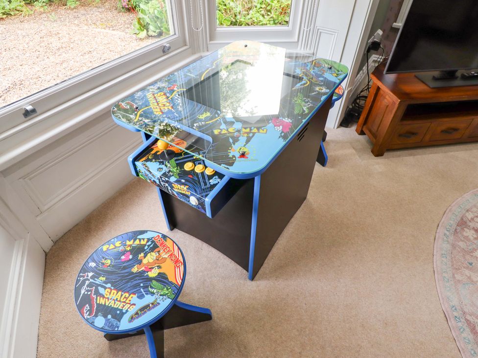 A desk with arcade graphics and a stool in a home office at 105 Spilsby Road, Boston