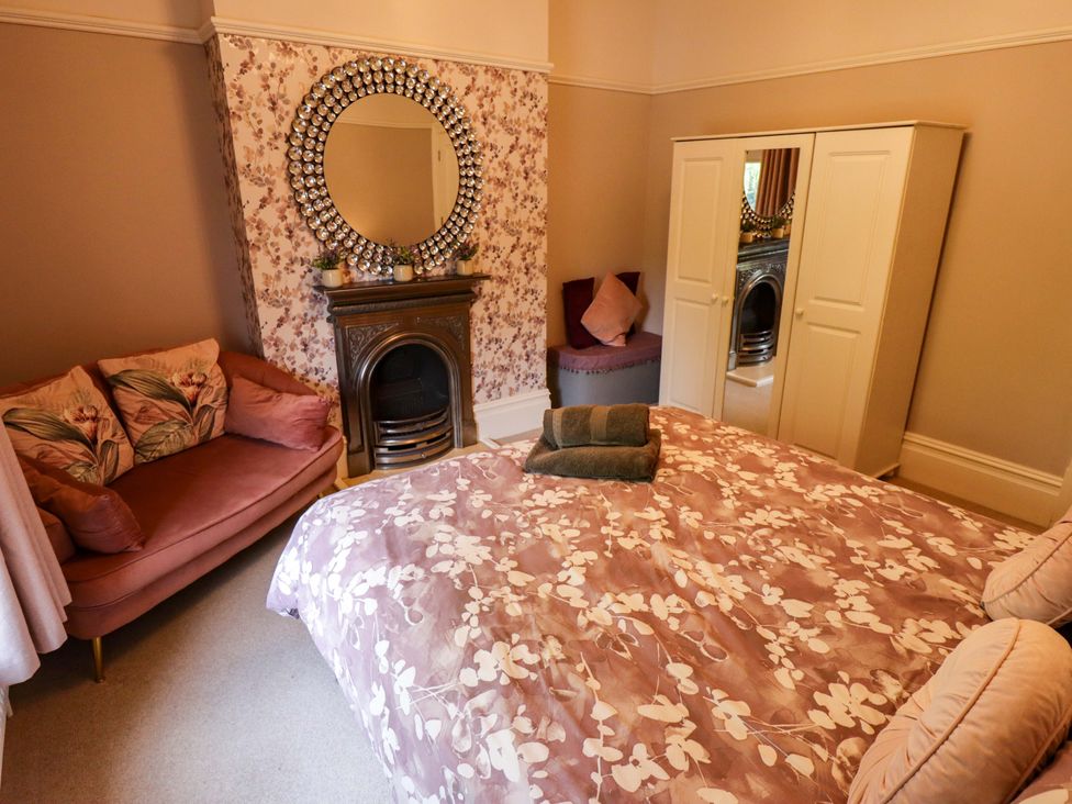 A bedroom featuring a bed, sofa, mirror, and wardrobe at 105 Spilsby Road in Boston