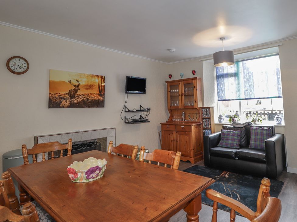 A dining room with wooden furniture and a television at Ivy House in Kingussie