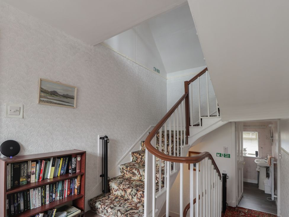 A hallway with a staircase and bookshelf at Ivy House in Kingussie