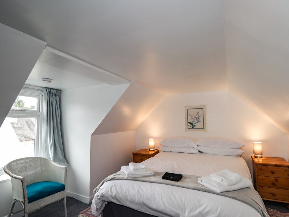 A bedroom with a bed and a chair at Ivy House in Kingussie