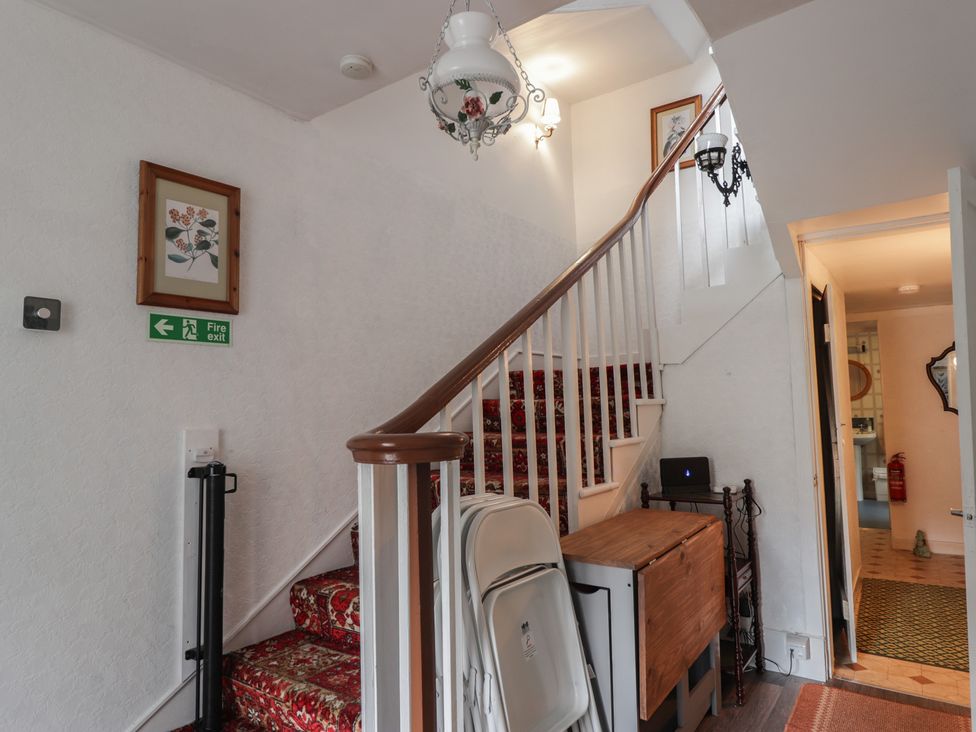 A hallway with a staircase and fire exit sign at Ivy House in Kingussie