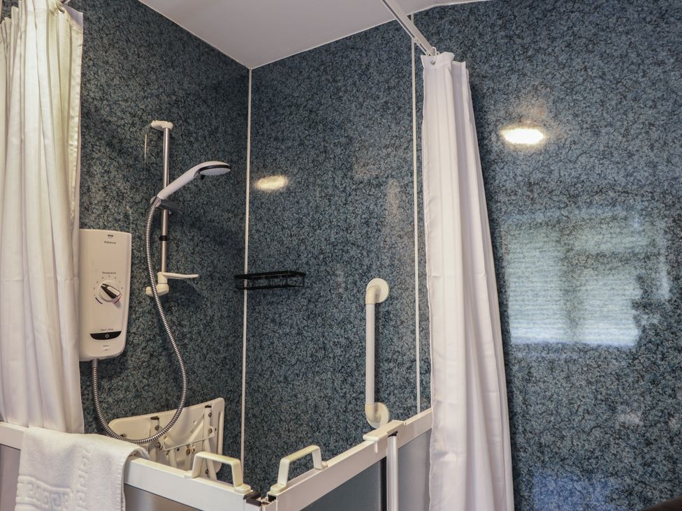 A shower area with a control panel and grab bar at Ivy House in Kingussie