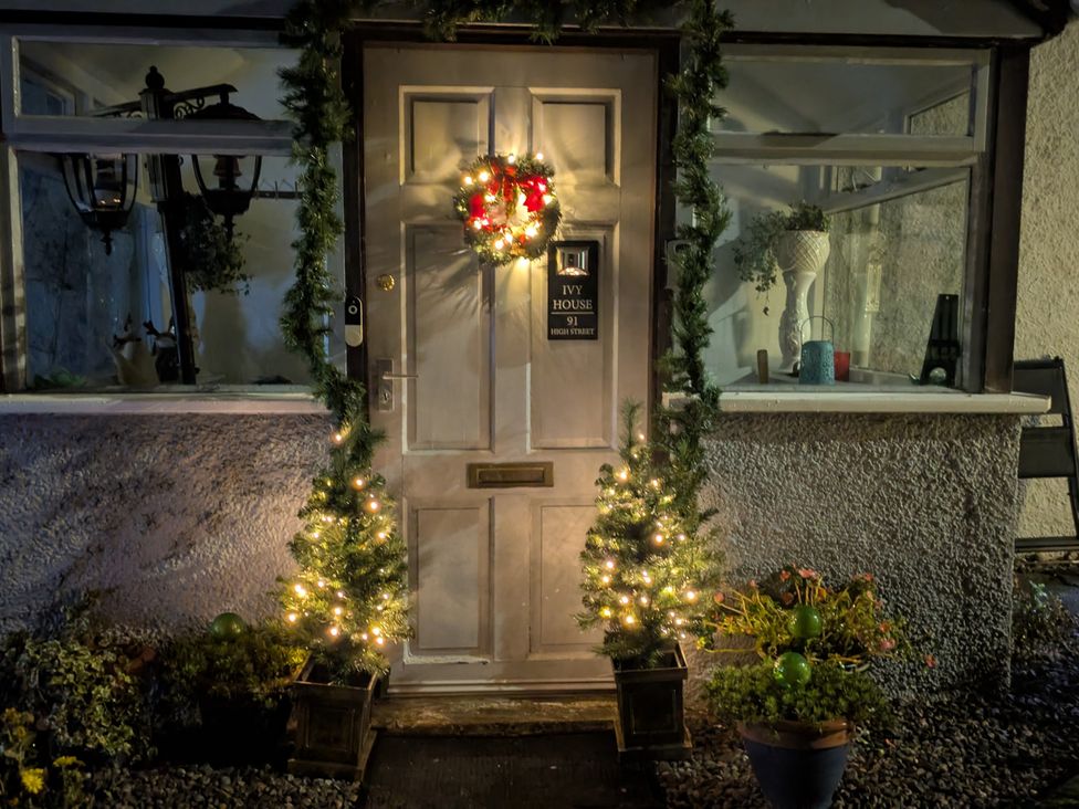 A door decorated with a wreath and lights at Ivy House in Kingussie