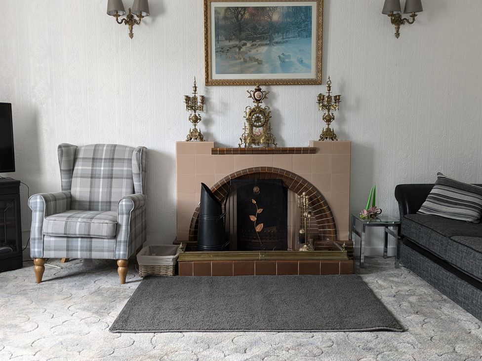 A living room with a fireplace and armchair at Ivy House Kingussie