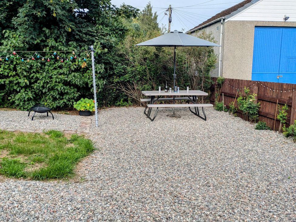 A garden with a table and umbrella at Ivy House in Kingussie