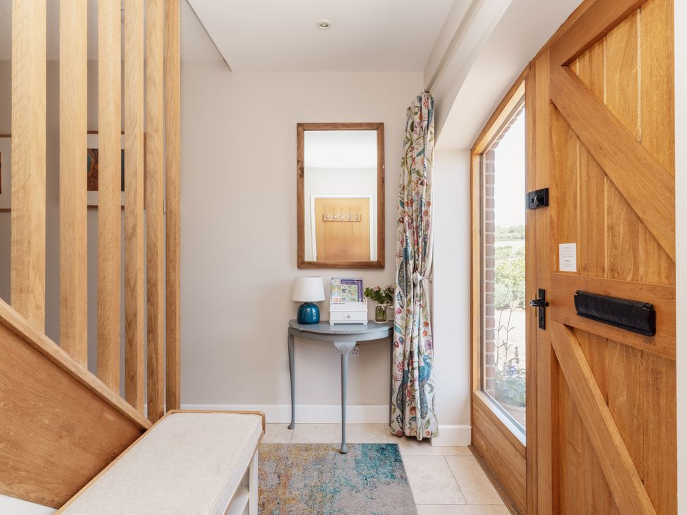 A hallway with a table, mirror, and a door at Tokenhill Cottage Piddletrenthide