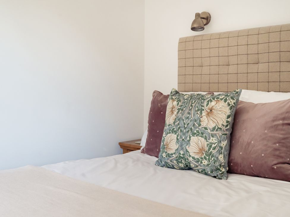 A bedroom with a bed and decorative pillows at Tokenhill Cottage in Piddletrenthide