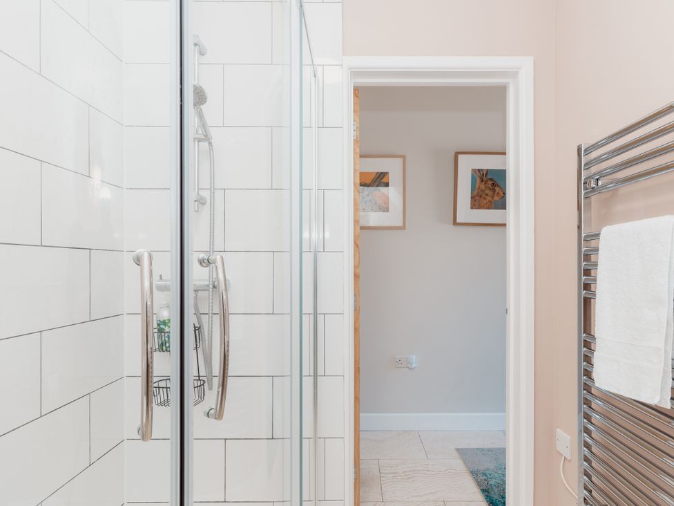 A shower with glass doors and a towel warmer at Tokenhill Cottage in Piddletrenthide