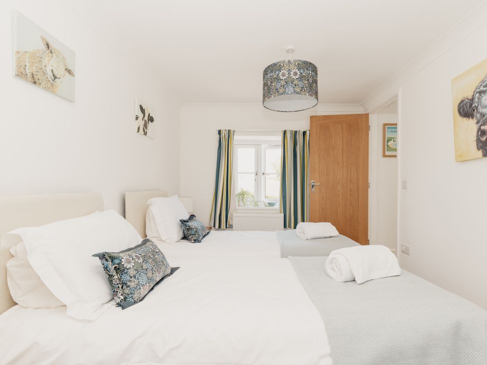 A bedroom with two beds and a window at Tokenhill Cottage in Piddletrenthide