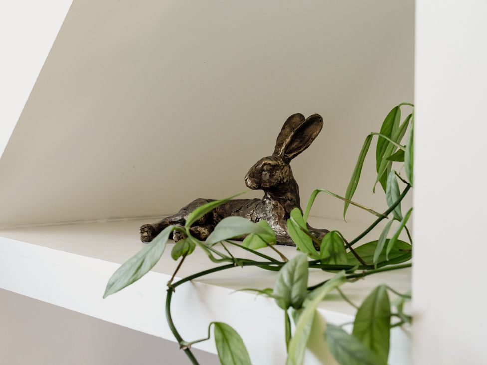A rabbit sculpture and plant on a shelf at Tokenhill Cottage in Piddletrenthide
