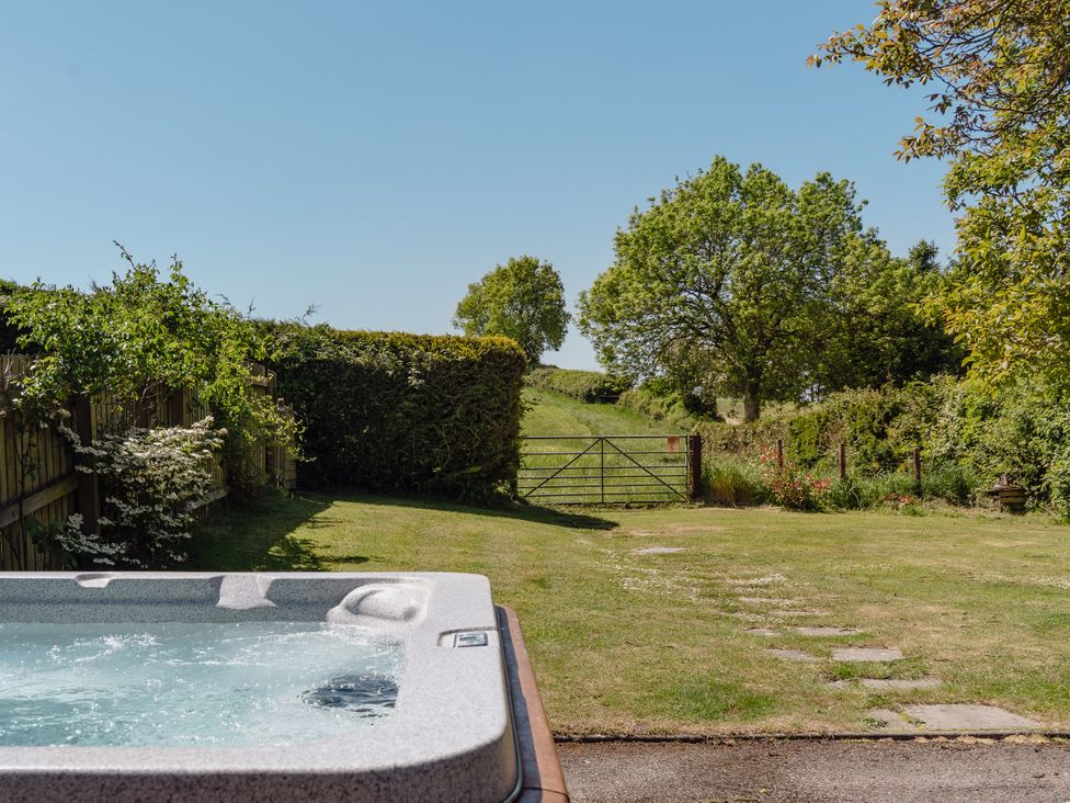 A garden with a hot tub and a view of a gate at Tokenhill Cottage in Piddletrenthide