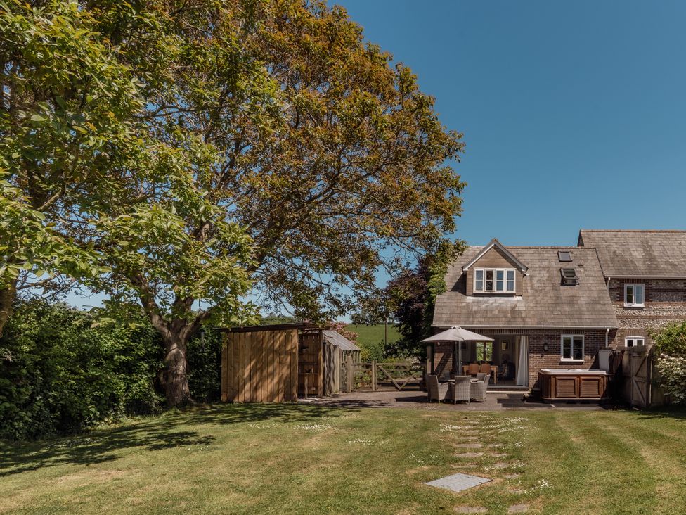 A garden with a house and hot tub at Tokenhill Cottage in Piddletrenthide