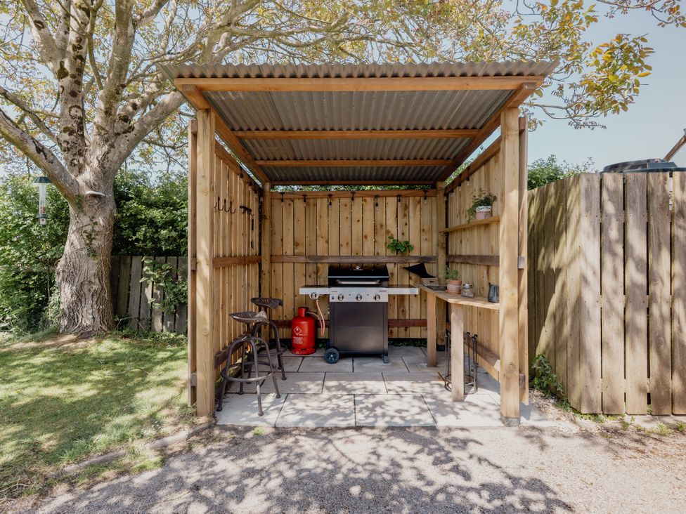 An outdoor kitchen with a grill and counter at Tokenhill Cottage in Piddletrenthide