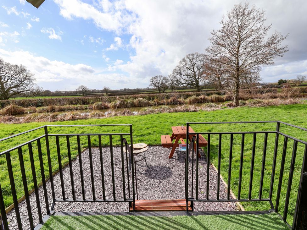 An outdoor area with a table and chairs overlooking grass at Quackin' Up