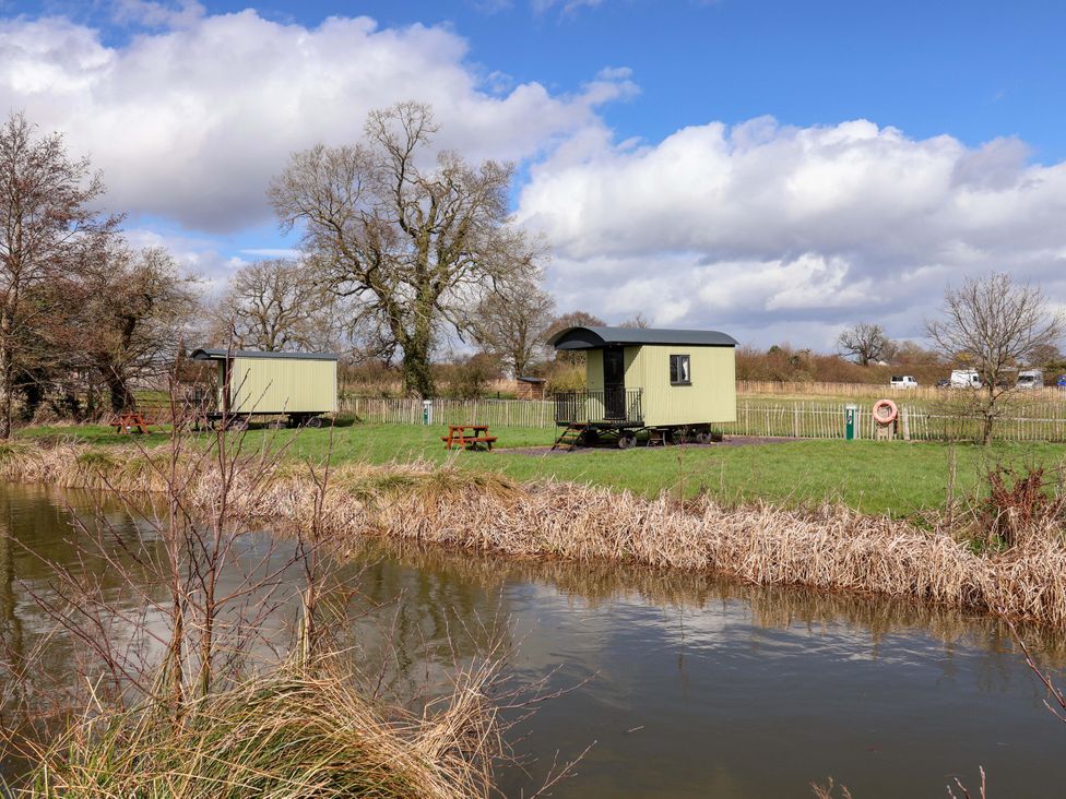 Two caravans by a pond with trees and benches at Quackin' Up