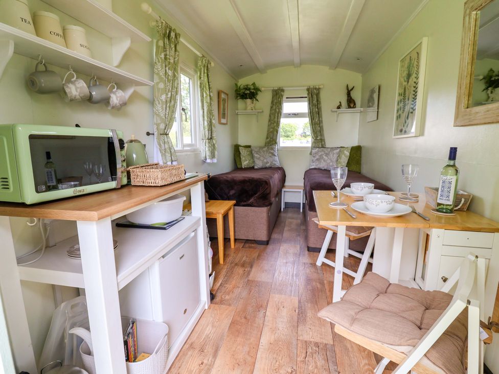 A living room with a microwave, table and chairs at Hop To It