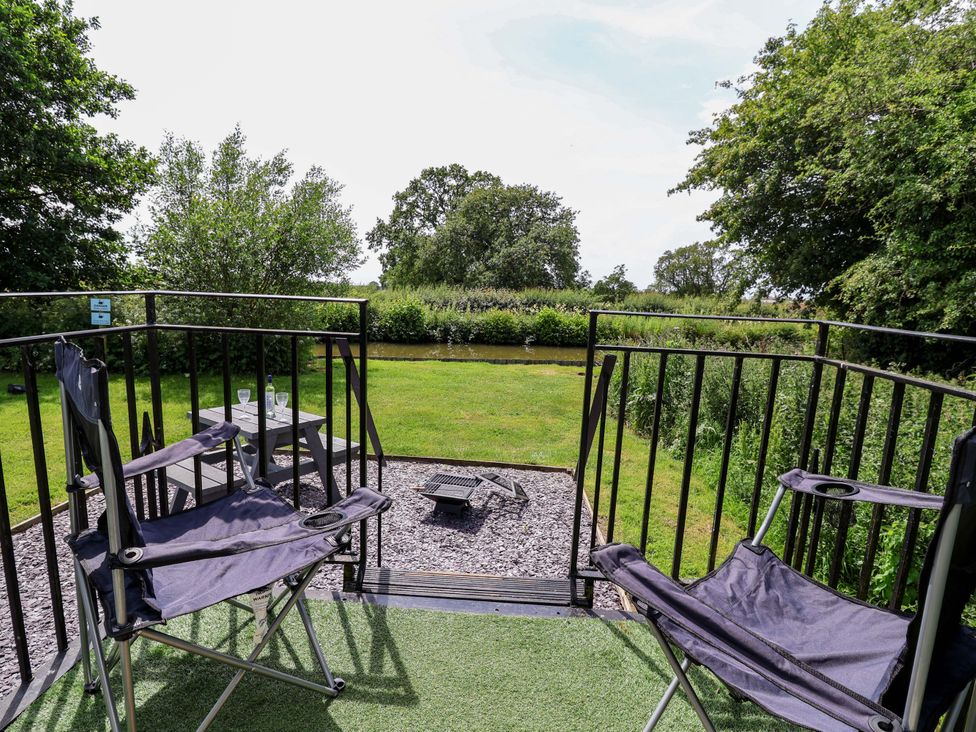 An outdoor seating area with chairs and a table overlooking green grass at Hop To It