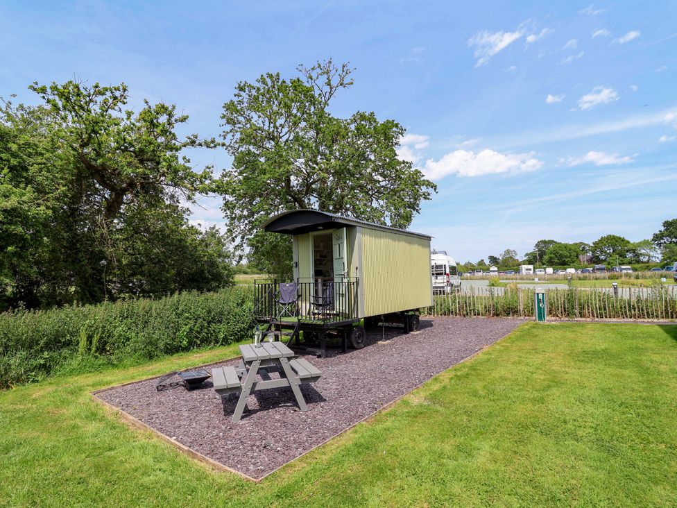 An outdoor area with a tiny house and seating table at Hop To It