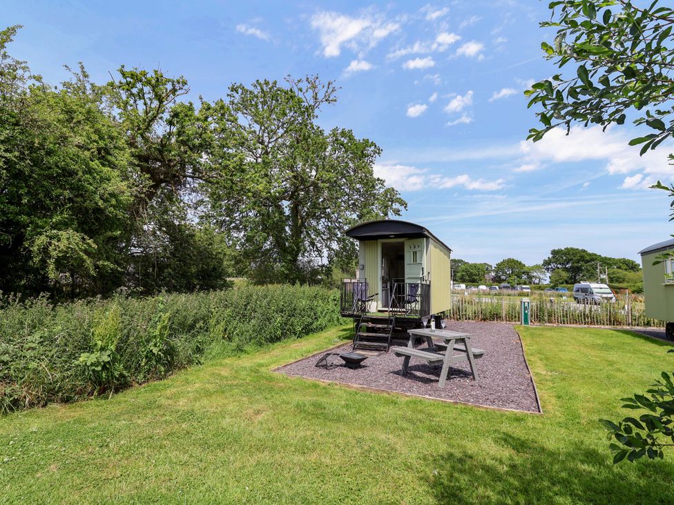 A tiny house with stairs and picnic table in an outdoor area at Hop To It