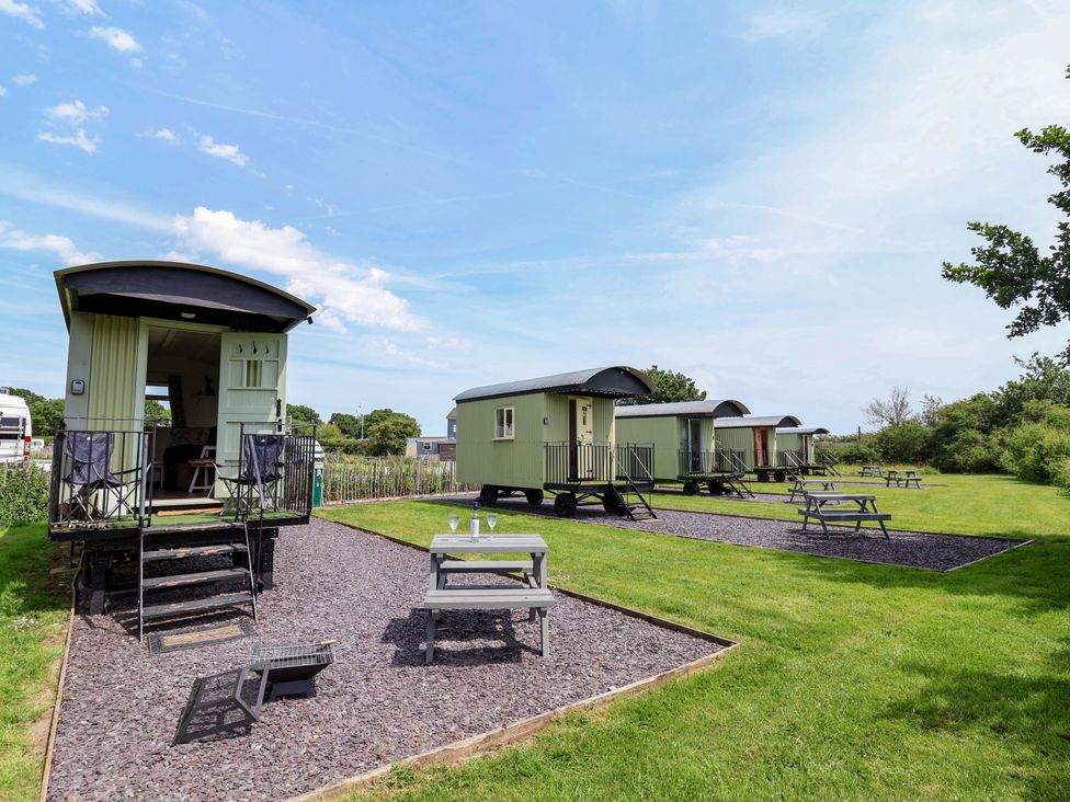 A view of three caravans with picnic tables in a garden at Hop To It