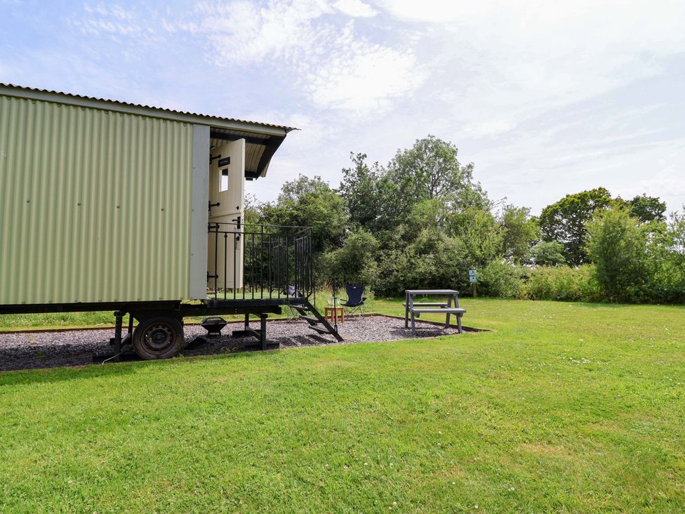 A shepherd's hut with steps and outdoor seating at Sid's Nest