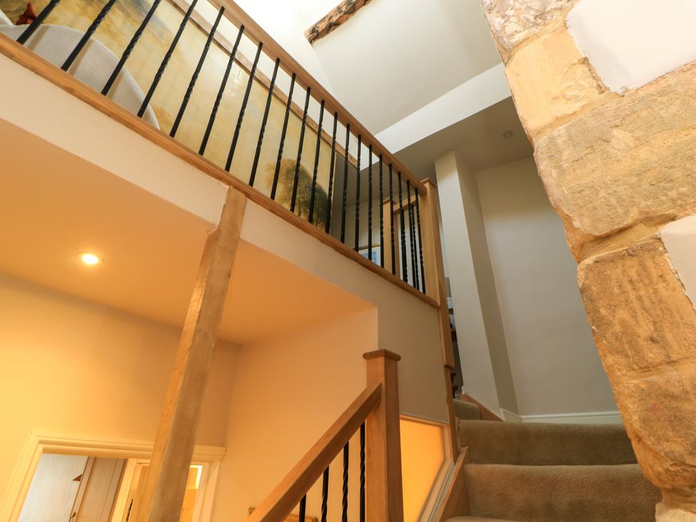 A staircase with wooden railing at Lower Pack Horse Cottage in Winchcombe