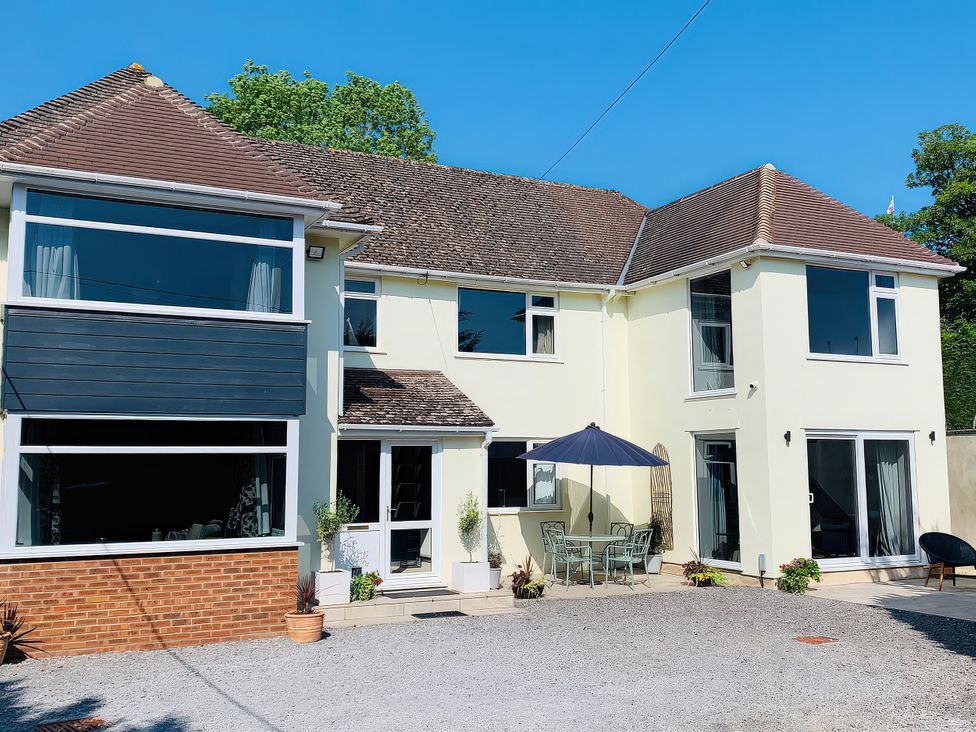 A house with outdoor seating and a parasol at Brooklands in Uplyme