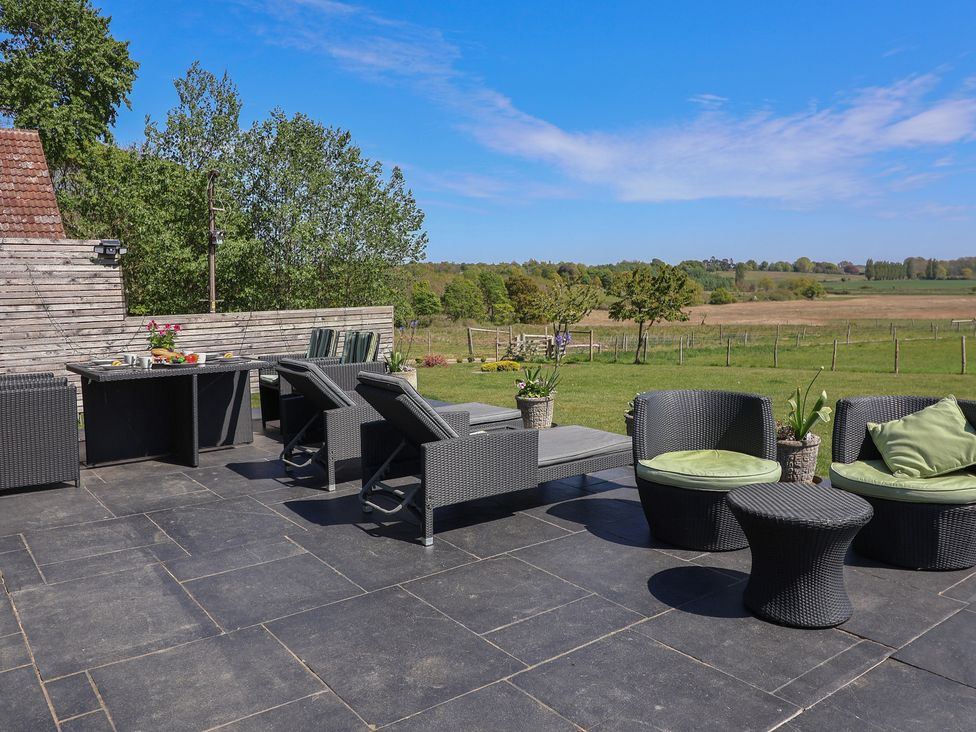 An outdoor seating area with a dining table and sun loungers at Polly's Annexe in Levington