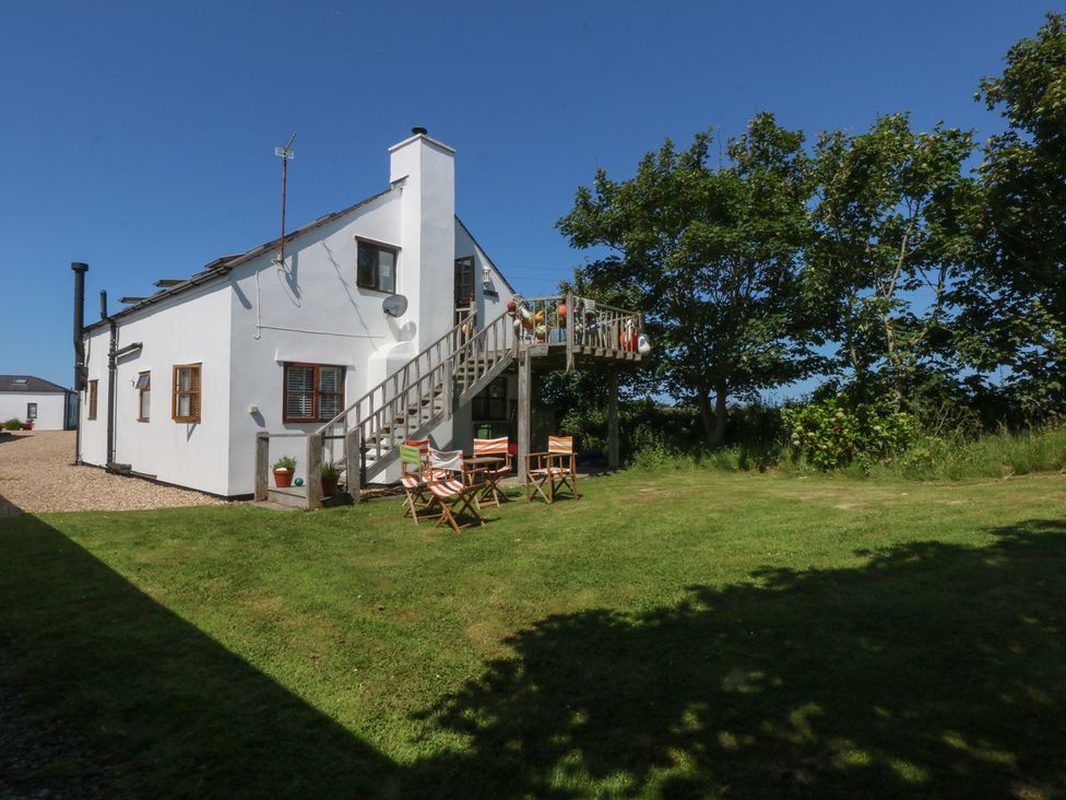 A house with a deck and staircase surrounded by grass at Borth Arian Boat House in Holyhead