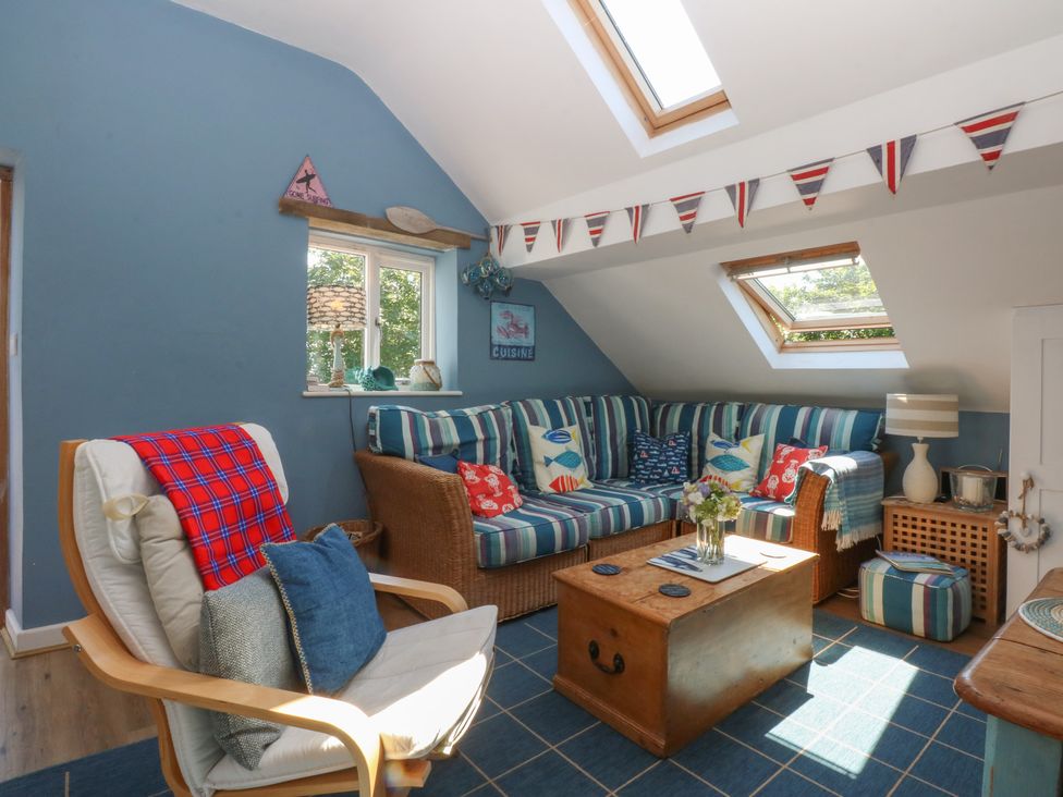 A snug with a sofa, armchair, and coffee table at Borth Arian Boat House in Holyhead