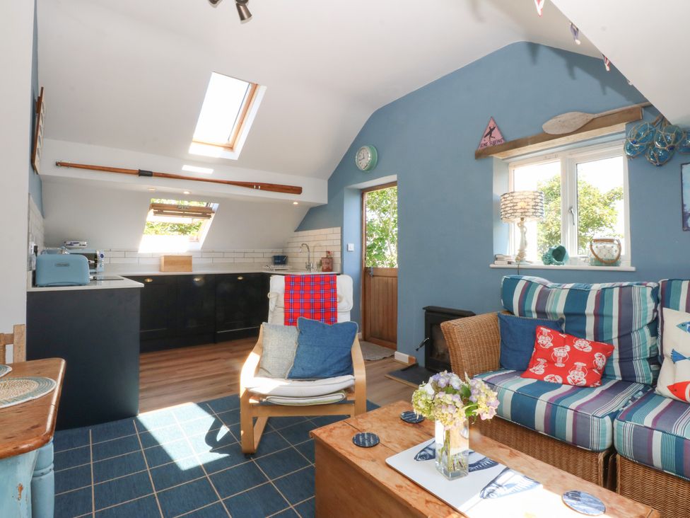 A living room with a kitchen area and seating at Borth Arian Boat House in Holyhead