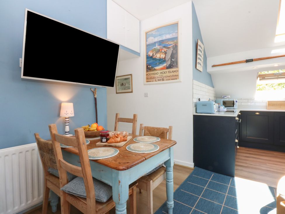 A kitchen with a dining area and television at Borth Arian Boat House in Holyhead