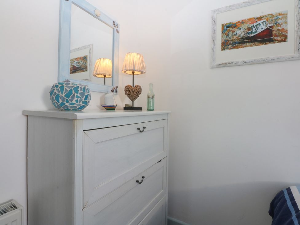 A bedroom with a chest of drawers and decorative items at Borth Arian Boat House in Holyhead