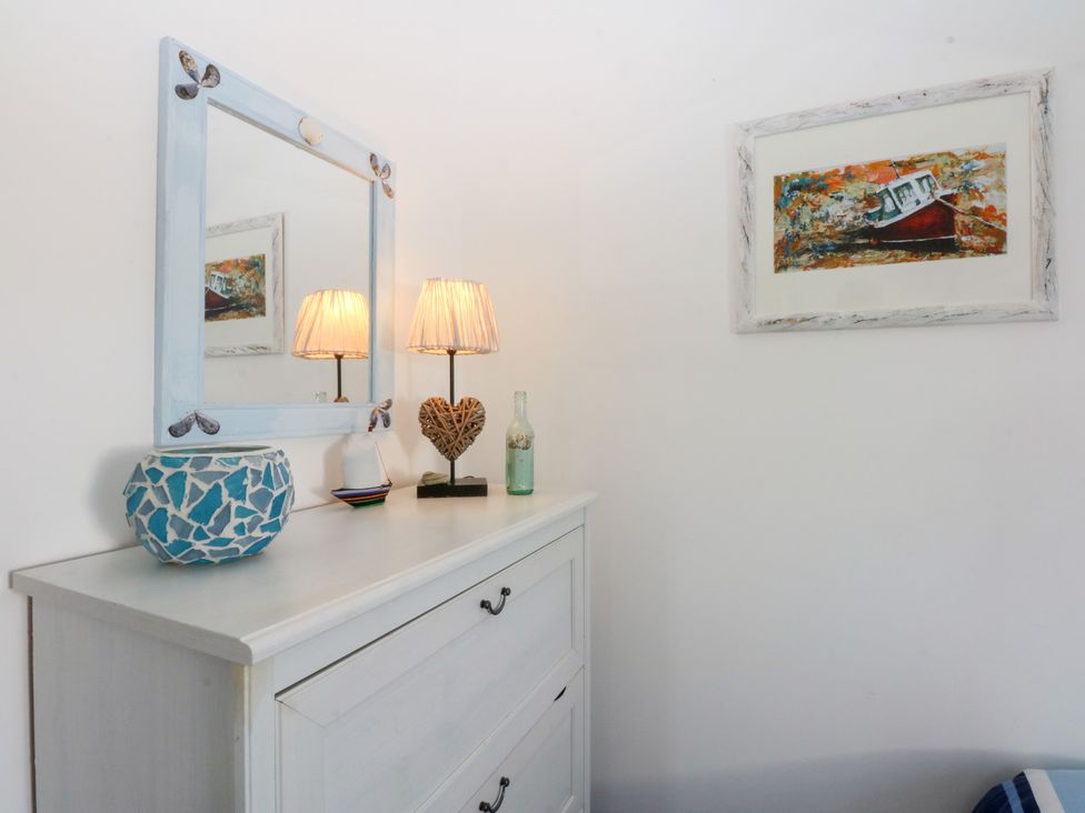 A bedroom with a mirror and lamps on a cabinet at Borth Arian Boat House in Holyhead