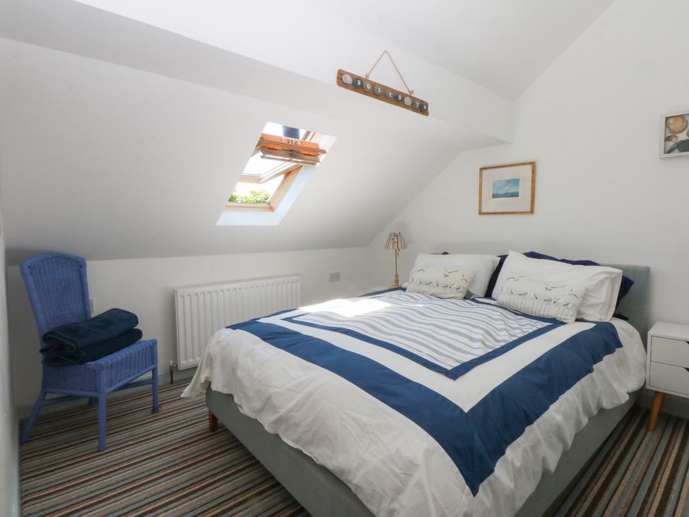 A bedroom with a bed, chair and lamp at Borth Arian Boat House in Holyhead