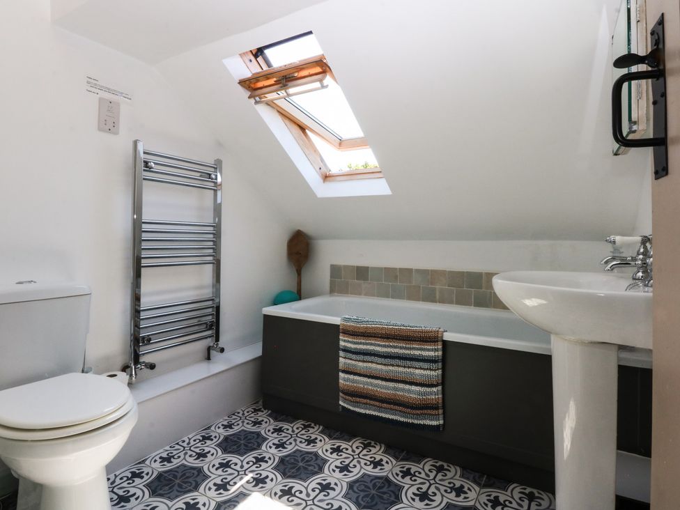 A bathroom with a toilet, sink, bath tub, and towel rack at Borth Arian Boat House, Holyhead