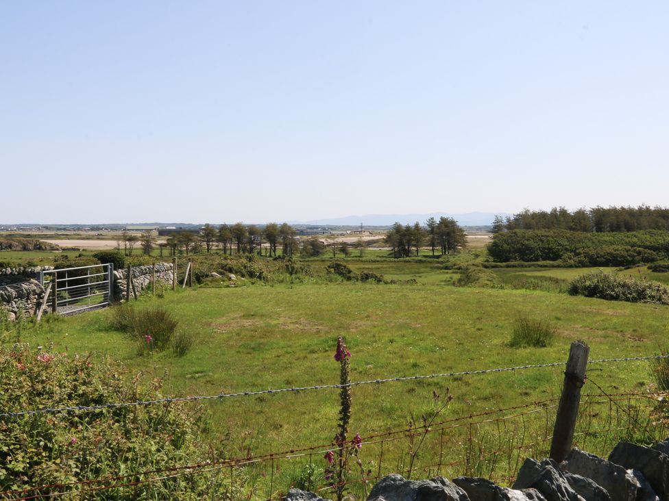A landscape with a gate and stone wall at Borth Arian Boat House Holyhead