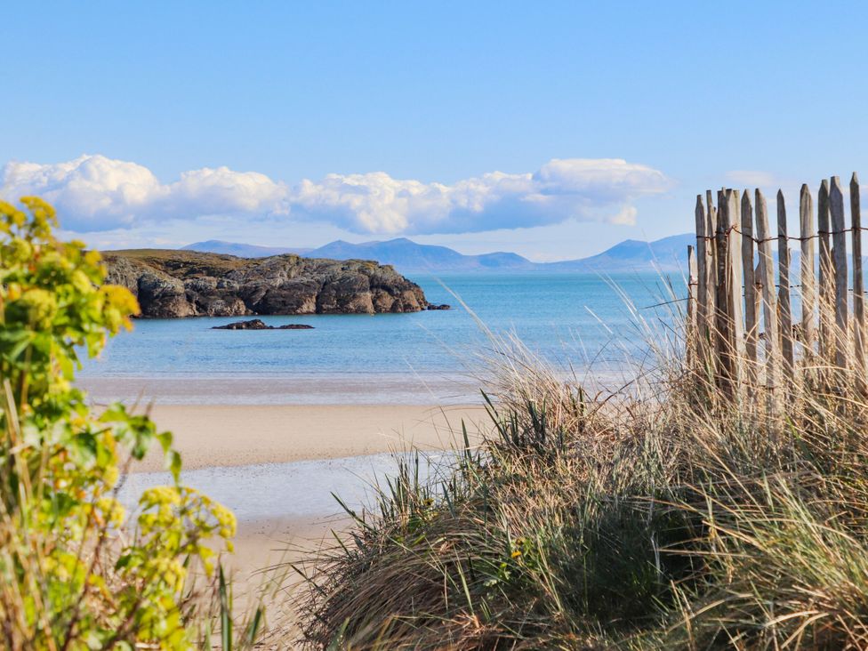 A beach view with water, sand, and rocks at Borth Arian Boat House in Holyhead