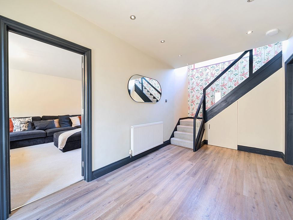 A hallway with a staircase and a sofa at 8 Newmarket Road in Royston