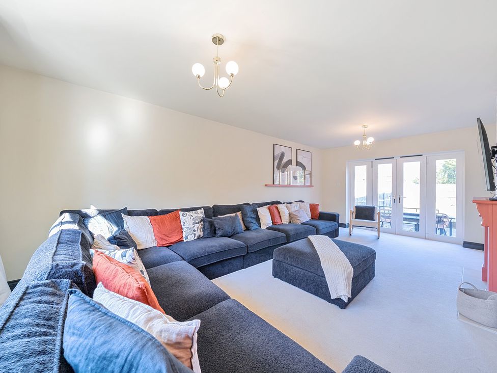 A living room with a large sofa and television at 8 Newmarket Road Royston